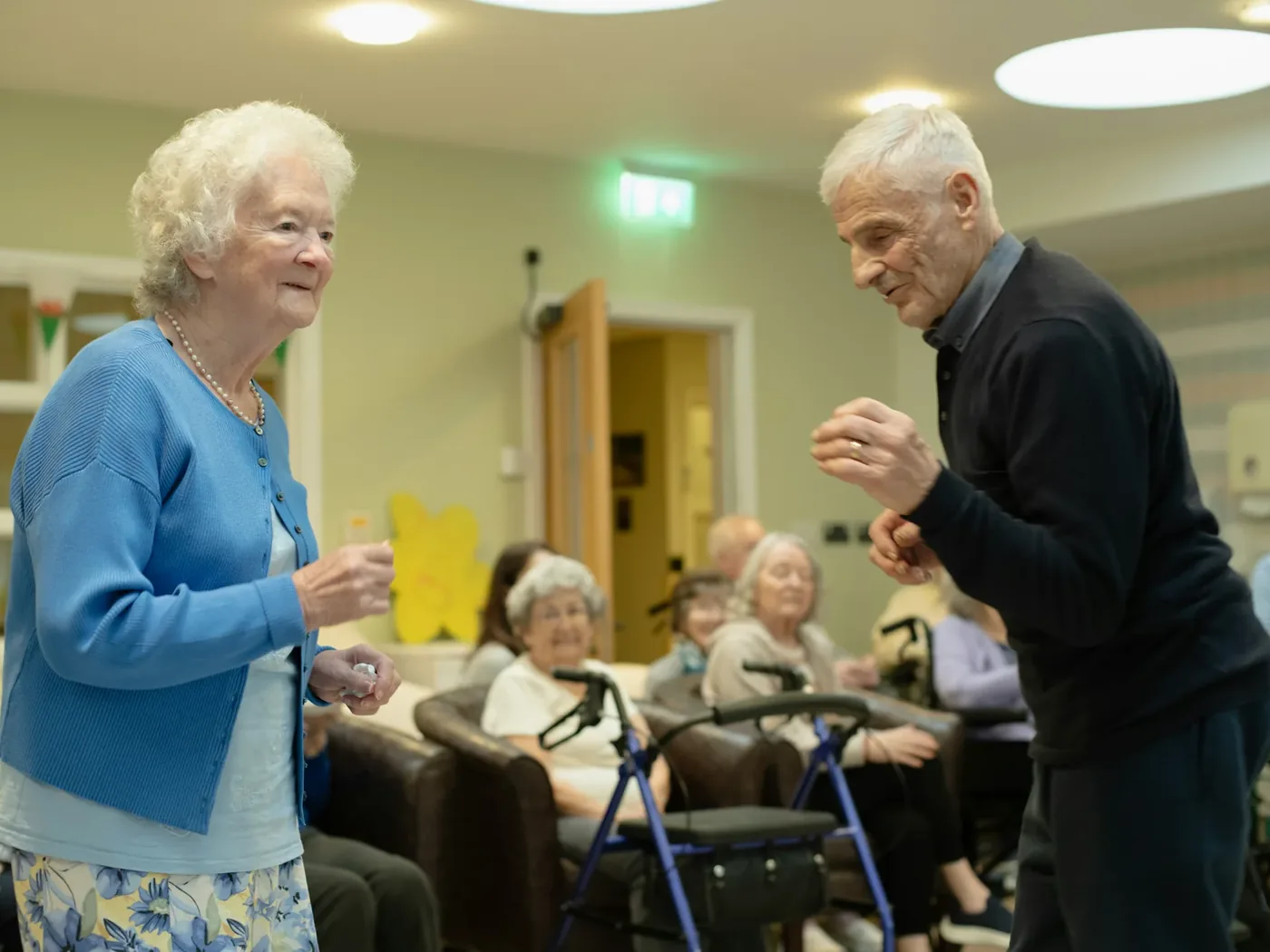 A music session in full swing, residents and staff moving to the music across a bright lounge