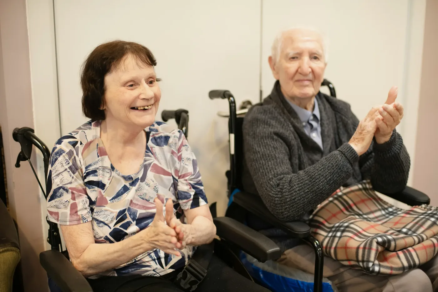 Two residents smiling and clapping along during a group music session