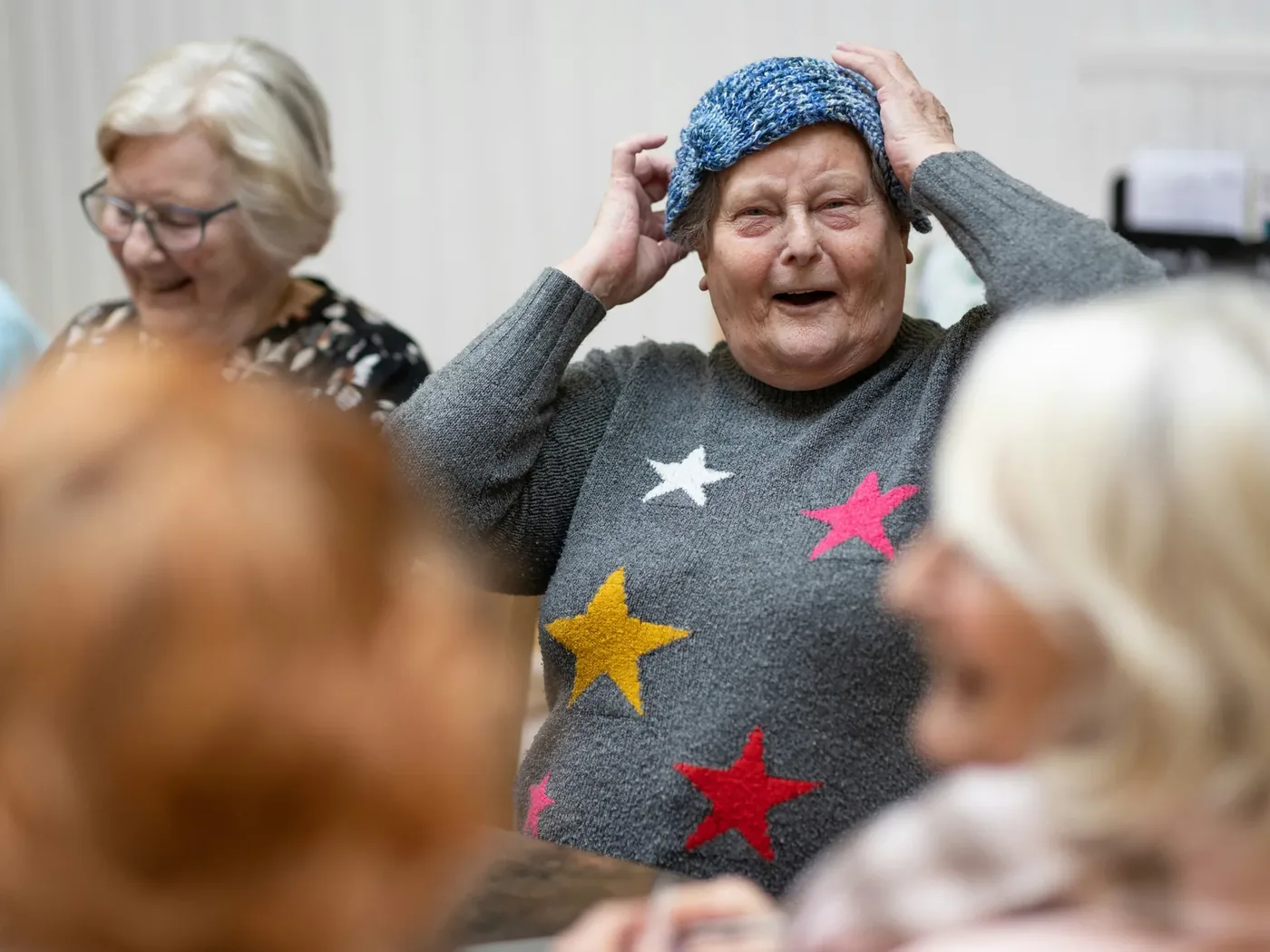 A facilitator leading a lively group music session, residents smiling and joining in