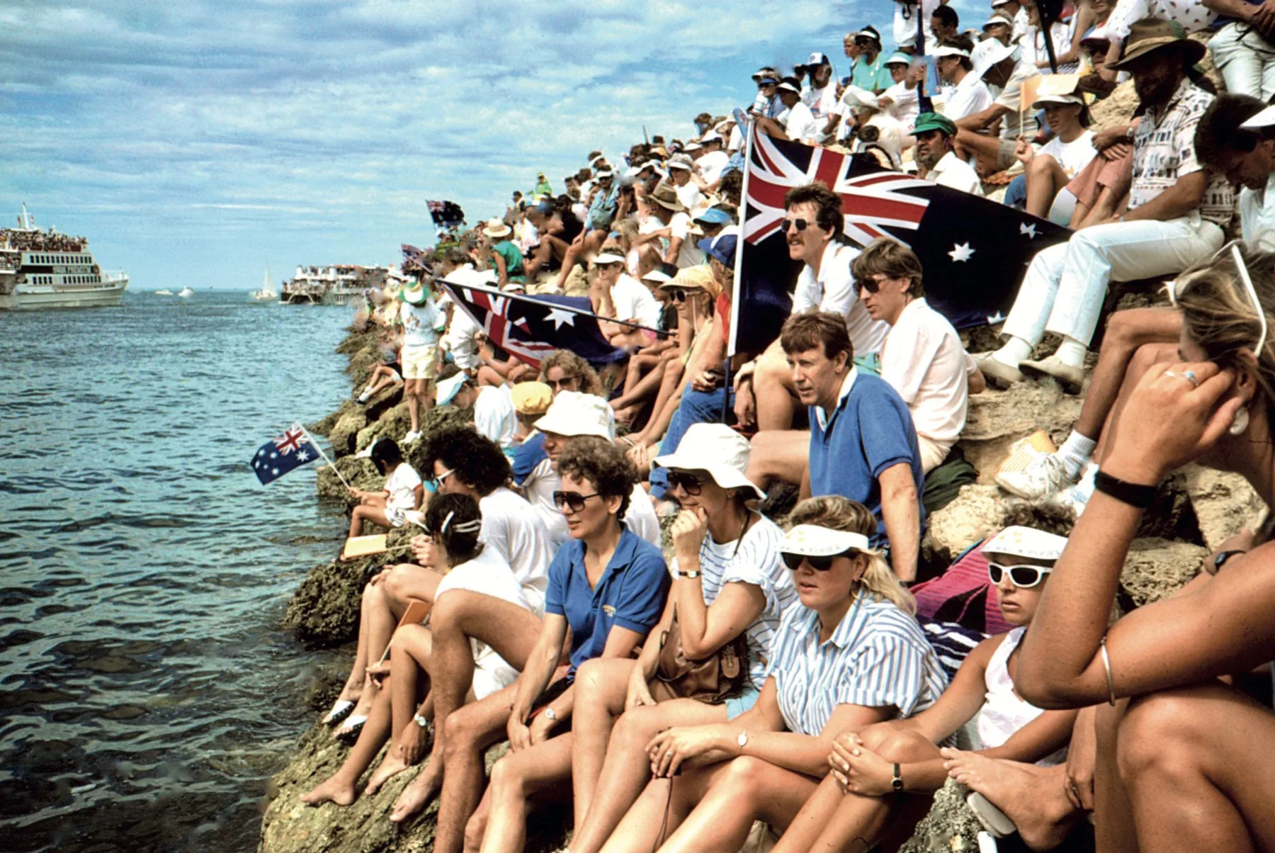 Crowds with Australian flags on the rocks at the Fremantle foreshore watching the 1987 America's Cup
